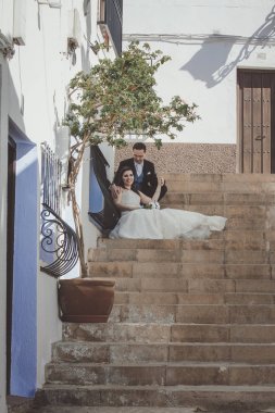 Onların düğün günü, bir Akdeniz köyde büyük bir merdiven üzerinde oturan genç çift