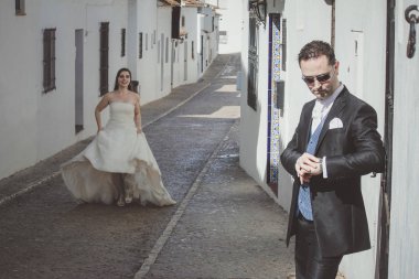 Sokakta genç düğün çifti. Damat bekliyor, gelin ona doğru çalışıyor