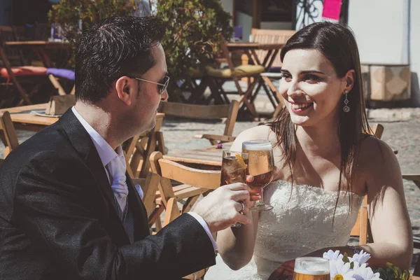 Young wedding couple on their wedding day, relaxing in a bar and having a beer — Stock Photo, Image