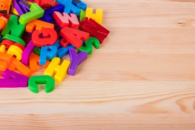 Bir okul ahşap masa üzerinde renkli manyetik harfler yığını