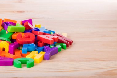 Bir okul ahşap masa üzerinde renkli manyetik harfler yığını