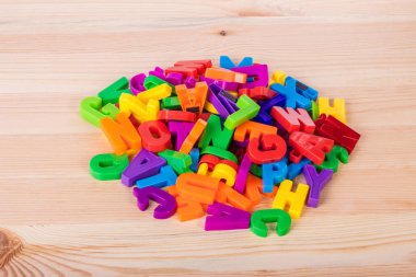 Bir okul ahşap masa üzerinde renkli manyetik harfler yığını