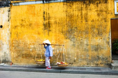 Hoi An, Quang Nam, Vietnam, 26 Nisan, 2018:Vietnamese kadın sokak satıcı Hoi antik kenti Hoi bir Vietnam'da bir tipik sarı evlerin manzaralı
