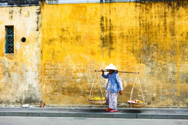 Hoi An, Quang Nam, Vietnam, 26 Nisan, 2018:Vietnamese kadın sokak satıcı Hoi antik kenti Hoi bir Vietnam'da bir tipik sarı evlerin manzaralı