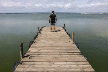 Sabah gökyüzünde göl tarafından bir dock adam