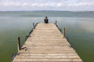 Sabah gökyüzünde göl tarafından bir dock adam