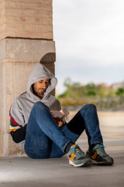 Genç Sakallı Adam, sabah vakti parkta oturmuş kitap okuyor..