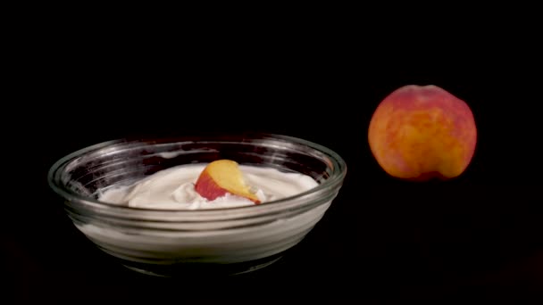 手把一片桃子放在一个有奶油的盘子里 放在一个黑色孤立的背景上 从带有人工专业照明的三脚架上拍摄的特写 — 图库视频影像