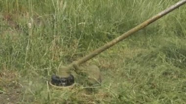 Ağır çekimde çalışırken benzin çim biçme makinesinin yakın çekimi. Yazın çim biçmek