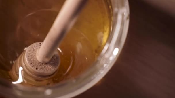 蜂の蜂蜜と蜂蜜の棒を持つガラス瓶のクローズアップ これは天然の健康食品です — ストック動画