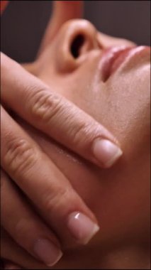 Güzellik uzmanı kadın kırışıklık önleyici yüz masajı yapıyor güzellik salonunda, yakın plan, dikey