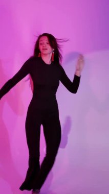 Bachata Lady Style, neon mor arka planda, genç esmer beyaz kadın dans eden kadın koreografisi. dikey, genel olarak yakın plan