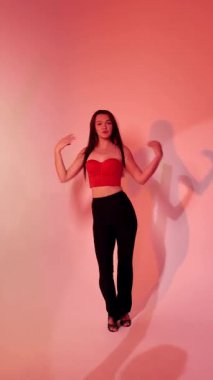 Kırmızı ışıklı arka planda Bachata Lady Style, genç esmer beyaz kadın dans eden kadın koreografisi. dikey, genel olarak yakın plan