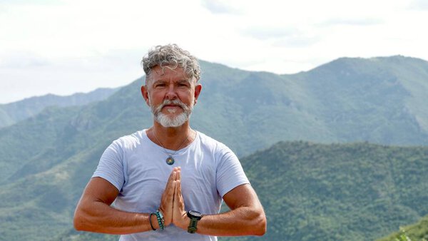 Portrait a senior man with gray hair and beard practicing meditation with prayer hands pose outdoors. spiritual practice, and mindfulness in nature