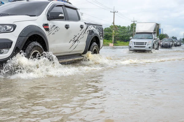 Carros dirigindo em uma estrada inundada, o carro quebrado está estacionado em um fl — Fotografia de Stock