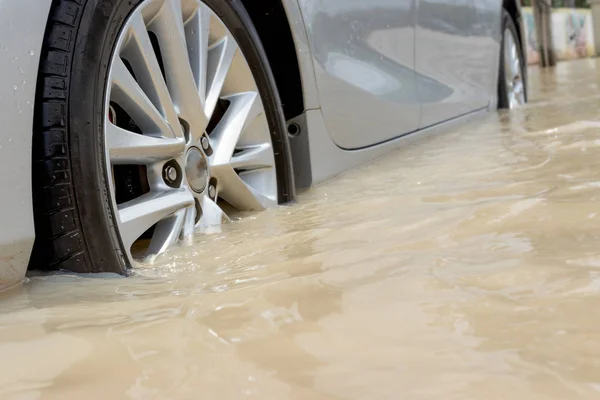 Carro dirigindo em uma estrada inundada, o carro quebrado está estacionado em um fl — Fotografia de Stock