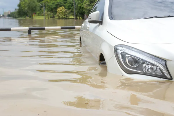 Carro dirigindo em uma estrada inundada, o carro quebrado está estacionado em um fl — Fotografia de Stock