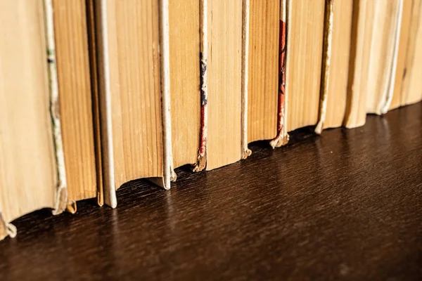 Old shabby books in cupboard in shelf