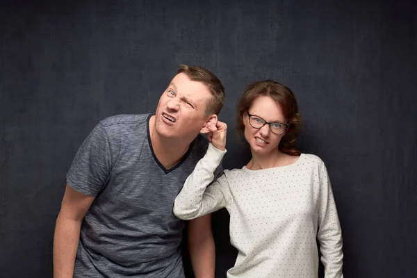 Dissatisfied woman is pulling naughty man by ear