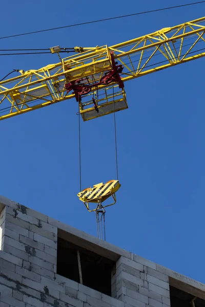 Shot of jib of yellow crane near building partially constructed