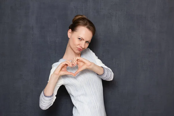 Portrait of comical flirty sexy girl making heart gesture