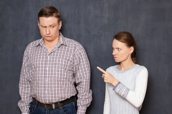 Angry dissatisfied short woman is scolding sad unhappy tall man