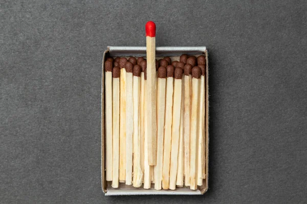 Matchbox full of matches is placed over gray background, with place for your text and design. One match is above other ones. Concept of leadership. Close-up shot, top view — Stock Image Matchbox Full Matches Placed Gray Background Place Your Text Design Royalty Free Stock Photos