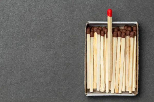 Matchbox full of matches is placed over gray background, with place for your text and design. One match is above other ones. Concept of leadership. Close-up shot, top view — Stock Image Matchbox Full Matches Placed Gray Background Place Your Text Design Stock Picture