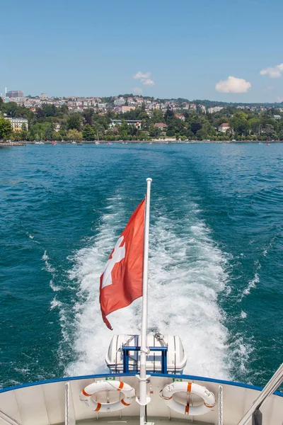 Barco de pasajeros con bandera suiza que sale del puerto de Lausana de Ouchy en el lago Leman (lago de Ginebra), Suiza, en un hermoso día soleado de verano. — Foto de Stock