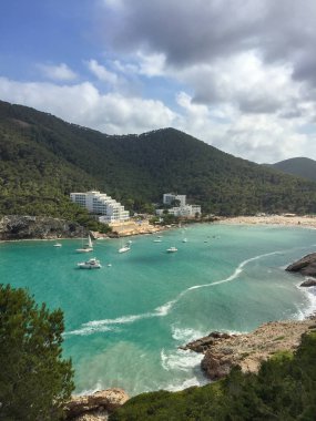 Güneşli yaz gününde beyaz bulutlarla dolu güzel Akdeniz Cala Llonga Koyu, İbiza Adası, İspanya