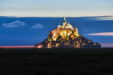 Işıklı Mont Saint Michel yaz aylarında bulutlar ile renkli bir gökyüzünde alacakaranlıkta, Fransa