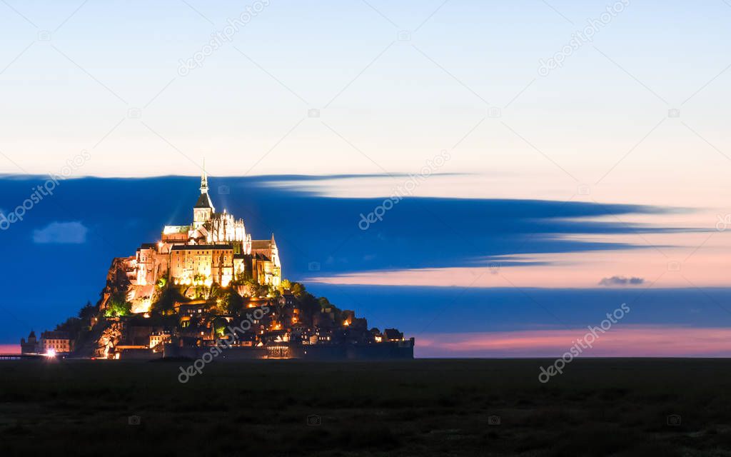 Illuminated Mont Saint Michel at dusk in a colourful sky with clouds on summertime, France