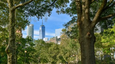 Battery Park'tan New York gökdelenleri. Ağaçların arasından.