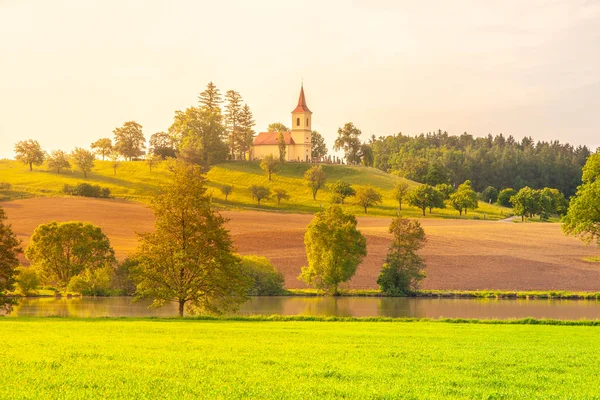Kleine kerk in het midden van de weelderige groene lente landschap op zonnige dag. Kerk van St. Peter en Pauls op Bysicky in de buurt van Lazne Belohrad, Tsjechië — Stockfoto