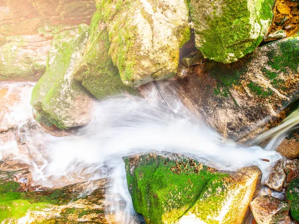 Cascata de água de pequeno riacho entre pedras musgosas. Exposição longa . — Fotografia de Stock