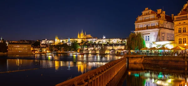 Praag door de nacht. Praagse burcht en Karelsbrug weerspiegeld in de rivier Vltava. Uitzicht vanaf Smetana Embankment. Praha, Tsjechië — Stockfoto