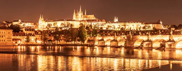 Praga dorada por la noche. Castillo de Praga y Puente de Carlos reflejados en el río Moldava. Vista desde Smetana Embankment. Praha, República Checa —  Fotos de Stock