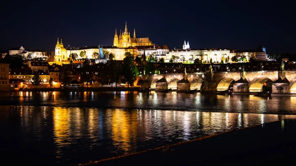 Praag door de nacht. Praagse burcht en Karelsbrug weerspiegeld in de rivier Vltava. Uitzicht vanaf Smetana Embankment. Praha, Tsjechië — Stockfoto