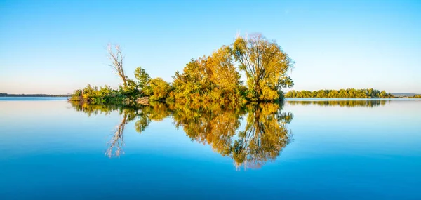 Small island with gren lush trees and clear blue sky reflected in calm water of Nove Mlyny Dam, Moravia, Czech Republic — Stock Photo, Image