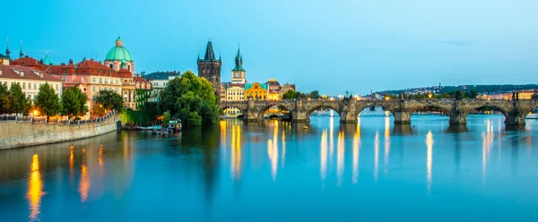 Verlichte Karelsbrug weerspiegeld in de rivier Vltava. Avond panorama van Praag, Tsjechië. Panoramische opname — Stockfoto