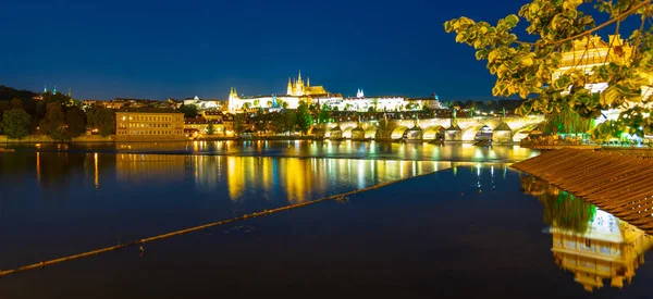 Praag door de nacht. Praagse burcht en Karelsbrug weerspiegeld in de rivier Vltava. Uitzicht vanaf Smetana Embankment. Praha, Tsjechië — Stockfoto