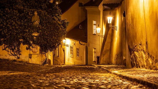Szűk macskaköves utcában, a középkori óváros megvilágított házak vintage utcai lámpák, Novy svet, Prága, Cseh Köztársaság. Lövés éjszaka — Stock Fotó