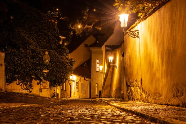 Smal kullerstensgata i medeltida stadskärna med upplysta hus av vintage gatlyktor, Novy svet, Prag, Tjeckien. Nattbild — Stockfoto
