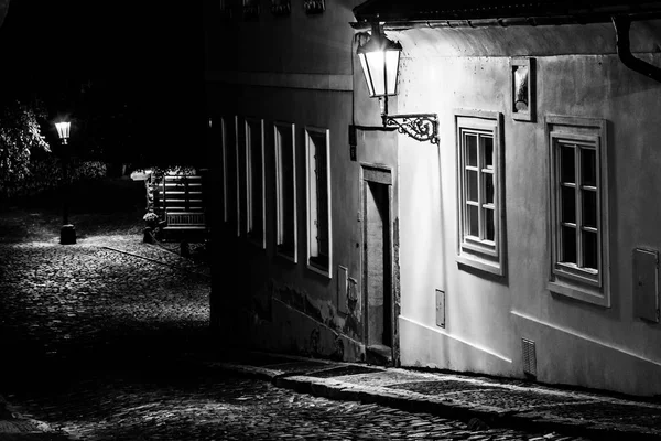 Rua de paralelepípedos estreita na cidade medieval velha com casas iluminadas por lâmpadas de rua vintage, Novy svet, Praga, República Checa. Tiro noturno — Fotografia de Stock