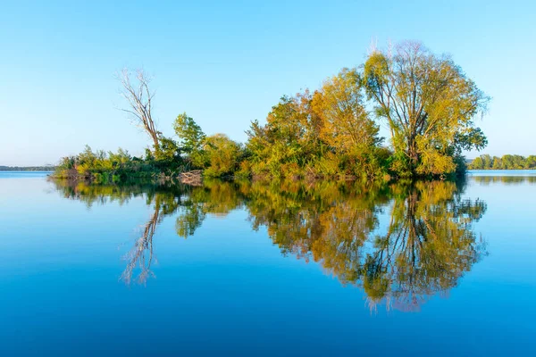 Small island with gren lush trees and clear blue sky reflected in calm water of Nove Mlyny Dam, Moravia, Czech Republic — Stock Photo, Image