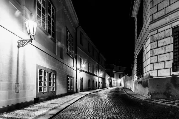 Rua de paralelepípedos estreita na cidade medieval velha com casas iluminadas por lâmpadas de rua vintage, Novy svet, Praga, República Checa. Tiro noturno — Fotografia de Stock