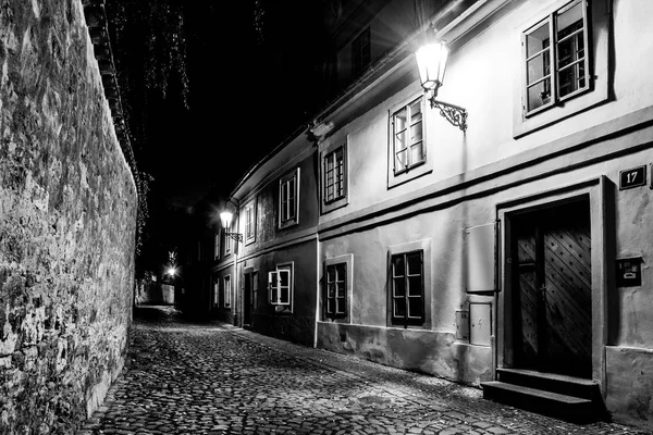 Estrecha calle empedrada en el casco antiguo medieval con casas iluminadas por farolas vintage, Novy svet, Praga, República Checa. Tiro nocturno —  Fotos de Stock