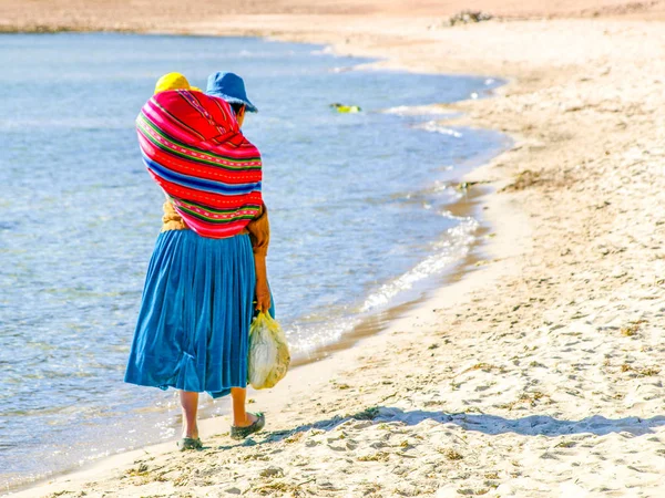 Mujer inca con el bebé en la bufanda de colores en la espalda. Paseos por la playa de Isla del Sol en el Lago Titicaca, Bolivia, América del Sur — Foto de Stock