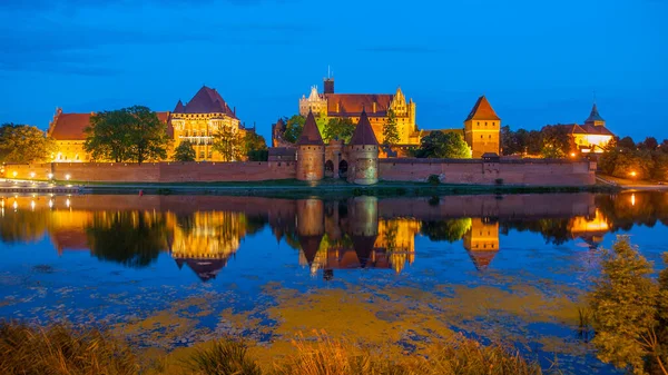 Vecchio castello teutonico di Malbork riflesso nel fiume Nogat di notte, Polonia — Foto Stock