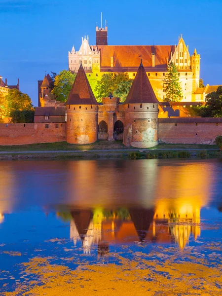 Antiguo Castillo Teutónico de Malbork reflejado en el río Nogat por la noche, Polonia — Foto de Stock